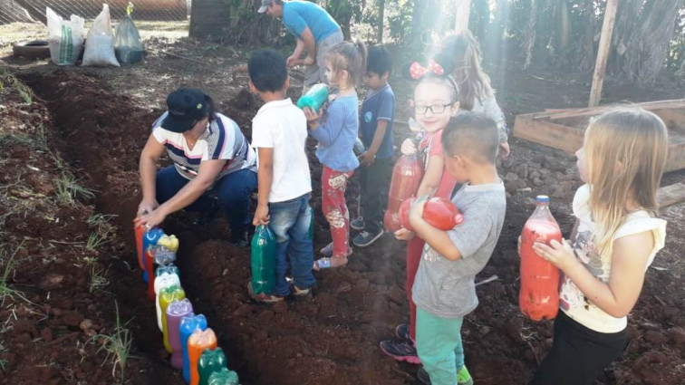 Turmas Da Educação Infantil da Escola Marcílio Dias constroem canteiro com garrafas pet na horta da escola